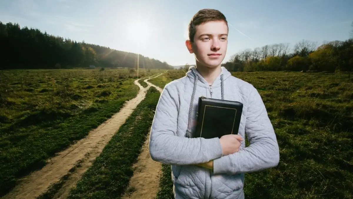 Jovem com a Bíblia e a estrada por onde deve escolher se vai. Ter uma visão clara do que queremos alcançar é o primeiro passo crucial na definição de metas que realmente funcionam. Hebreus 11:1 diz que "a fé é a certeza daquilo que esperamos e a prova das coisas que não vemos."
